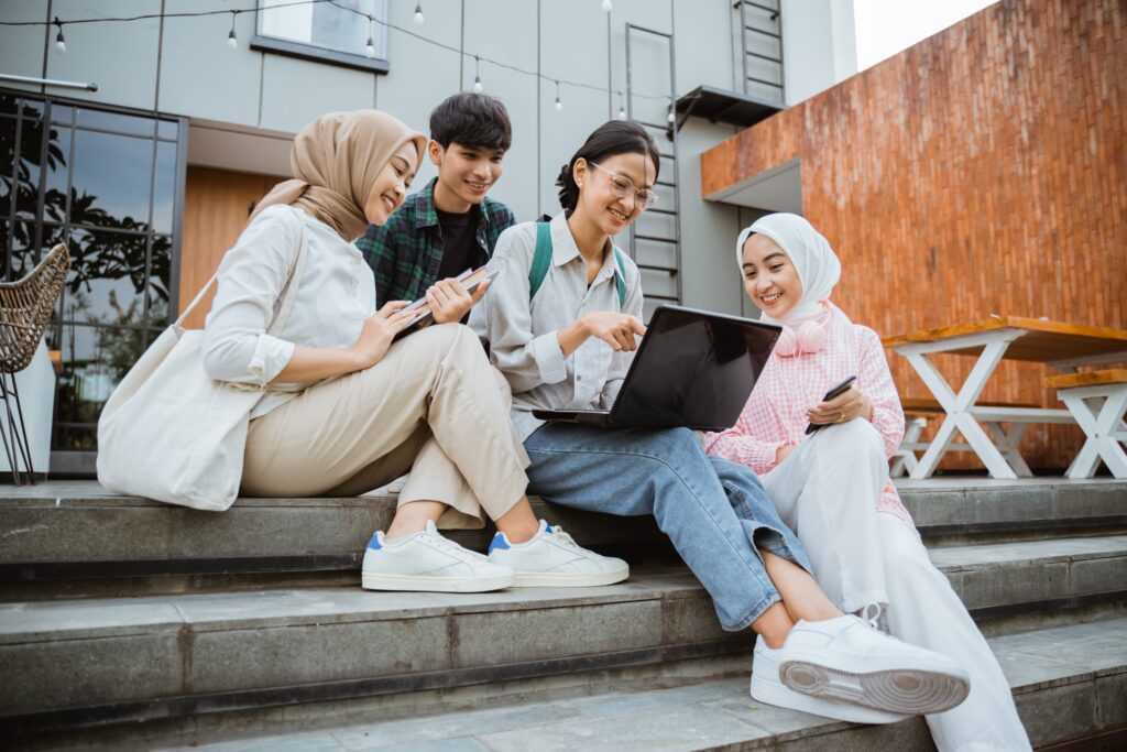 group,of,young,asian,students,using,laptops,sitting,on,steps