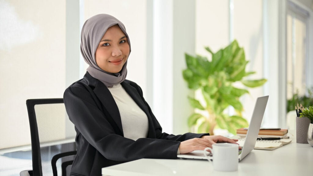 attractive asian muslim businesswoman looking camera while sitting her desk